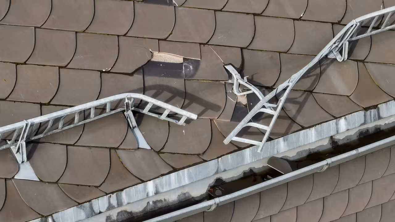 drohnenaufnahme eines beschädigten hausdachs mit dachschindeln und schneefanggitter in frankfurt