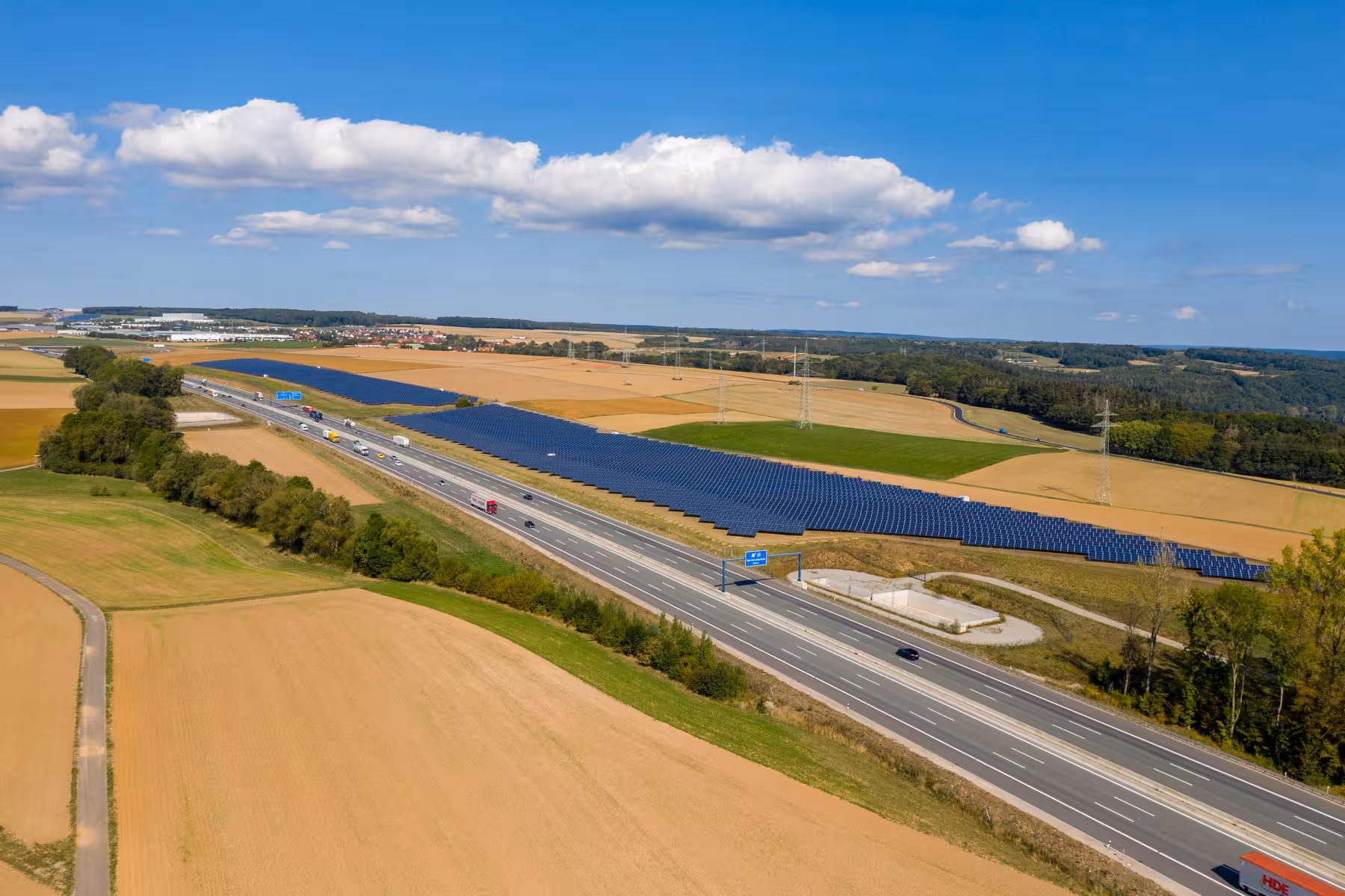 drohnenaufnahme eines solarparks in einer ländlichen, hügeligen gegend an der autobahn bei wertheim