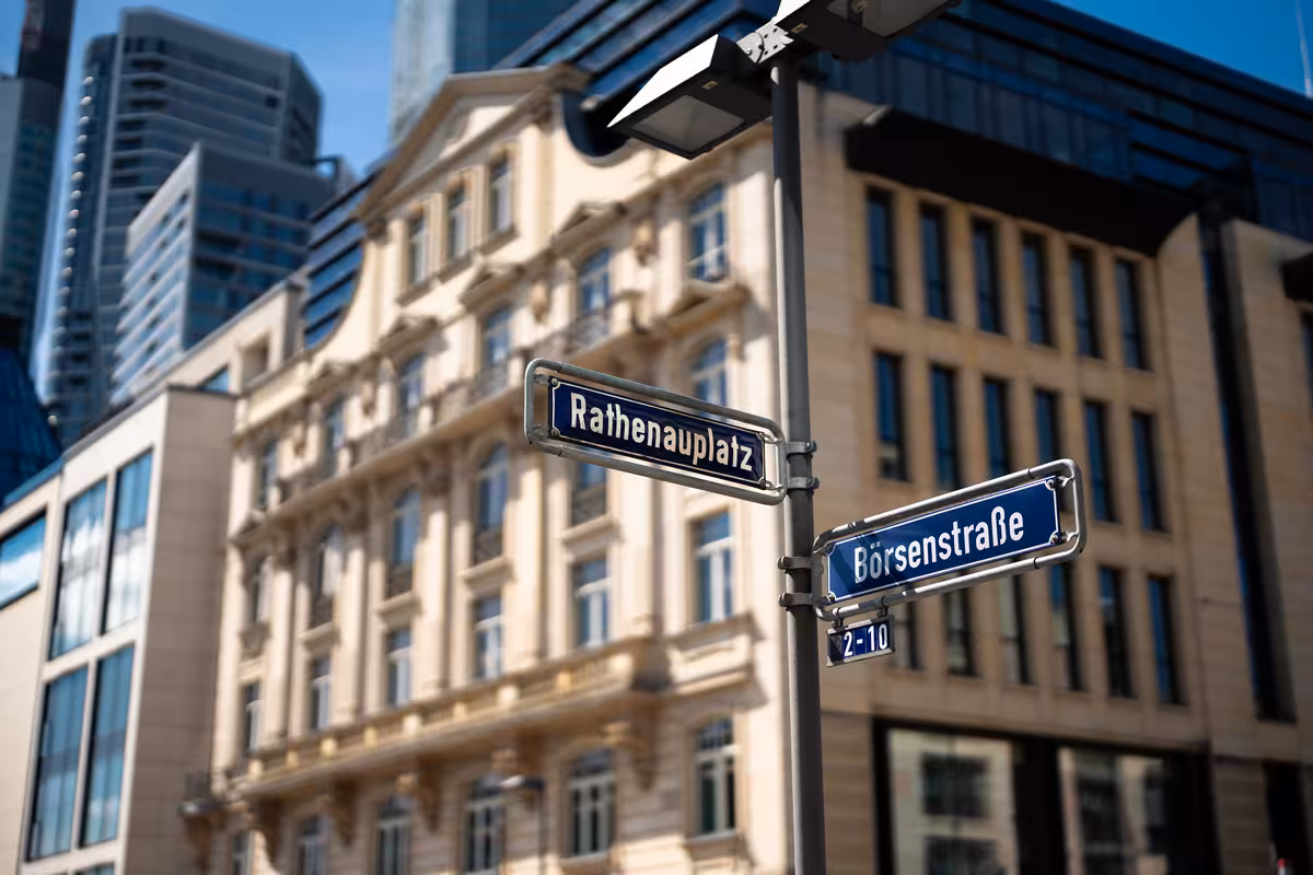 teleaufnahme einer straßenkreuzung mit einem historischen wohngebäude mit sandsteinfassade im hintergrund in frankfurt am main in der morgensonne für immobilienmarketing