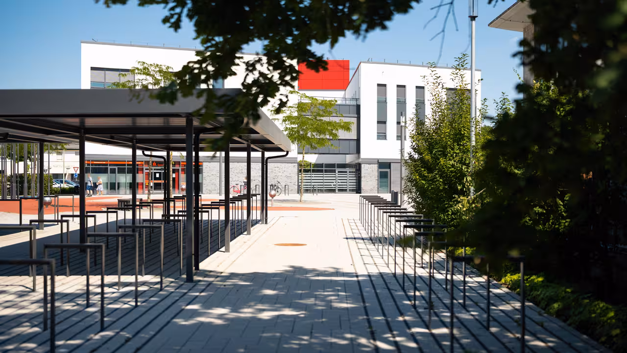 teleaufnahme überdachter fahrradständer mit bäumen im vordergrund am städtischen gymnasium in selm