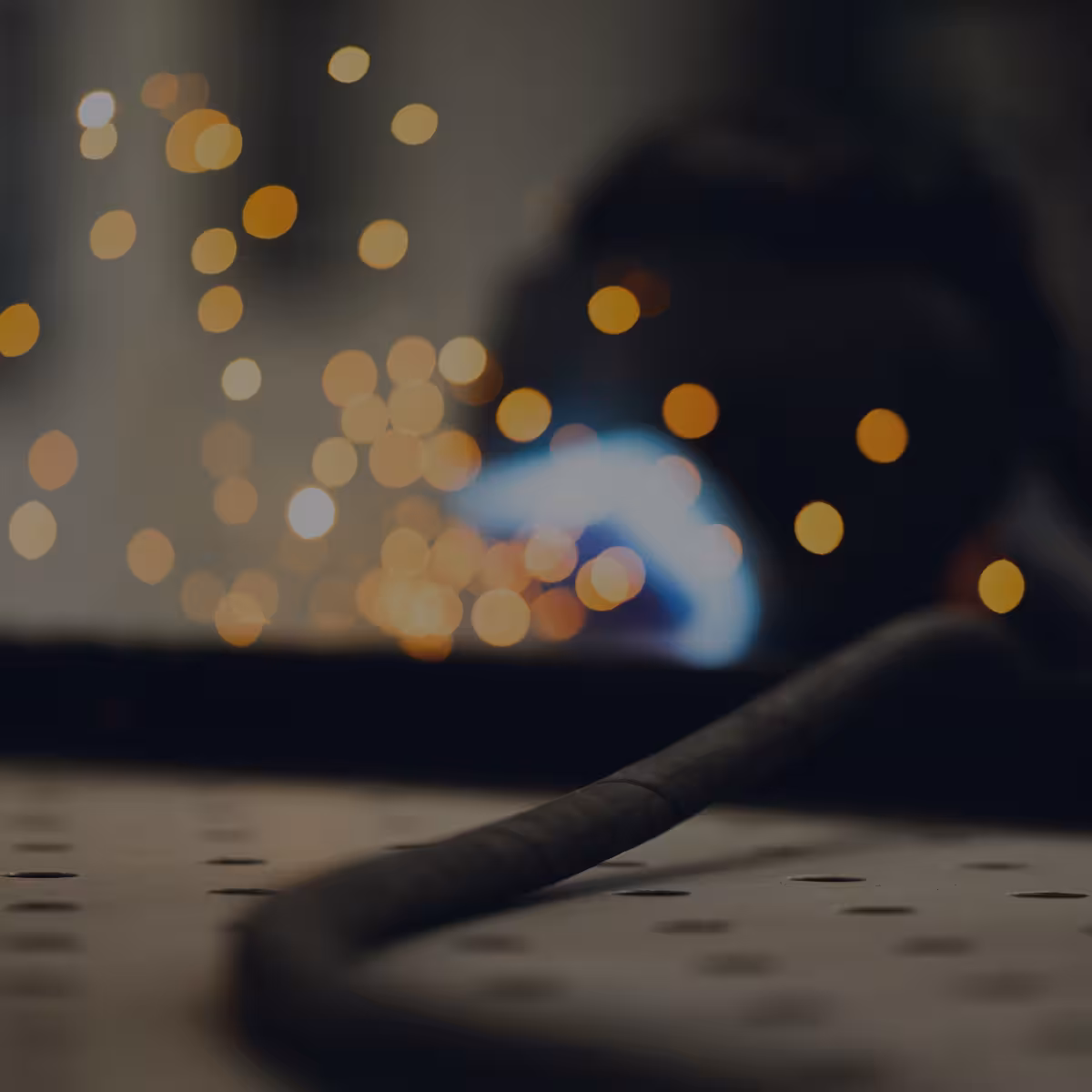 teleaufnahme eines mitarbeiters beim stahlschweißen mit funken im hintergrund bei korema in darmstadt für einen imagefilm dunkel