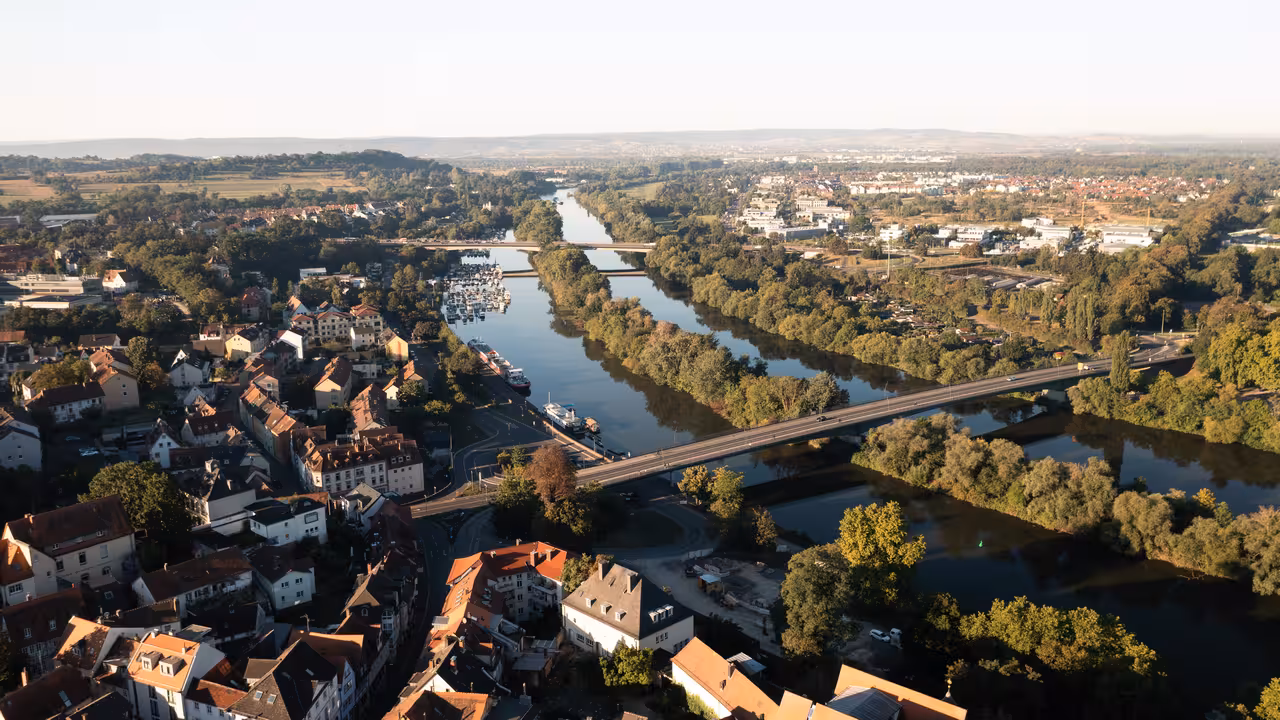 drohnenaufnahme der willigisbrücke und der adenauerbrücke im hintergrund über den main in aschaffenburg in der morgensonne während einer drohnenvermessung