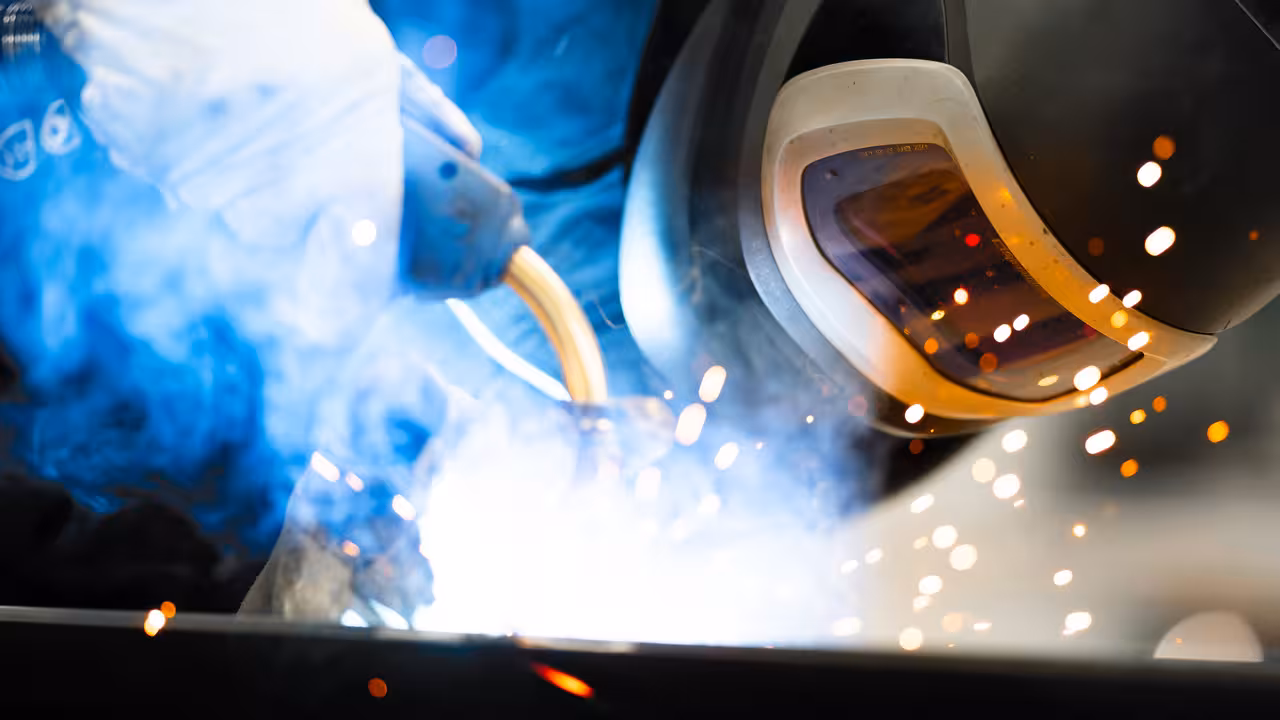 teleaufnahme eines mitarbeiters beim stahlschweißen mit funken im vordergrund bei korema in darmstadt für marketing