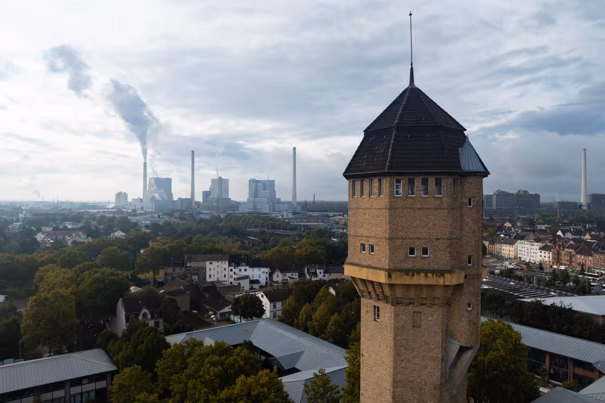 drohnenaufnahme eines mannheimer wasserturms mit den am rhein gelegenen großkraftwerken im hintergrund während dokumentationsarbeiten